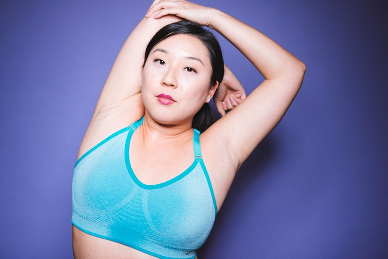 A woman stretching her shoulder and elbow in a blue sports bra