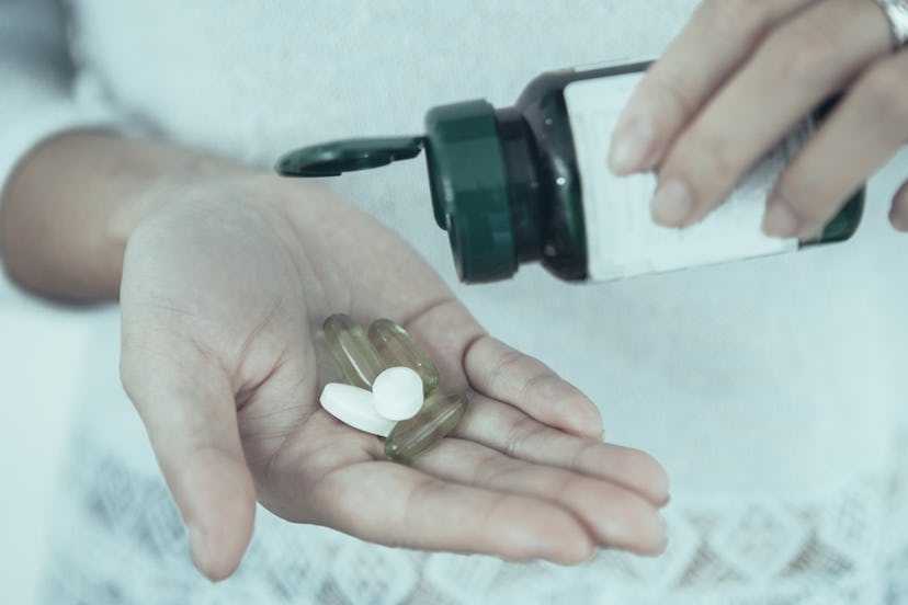 A woman taking a lot of pills from a pill container