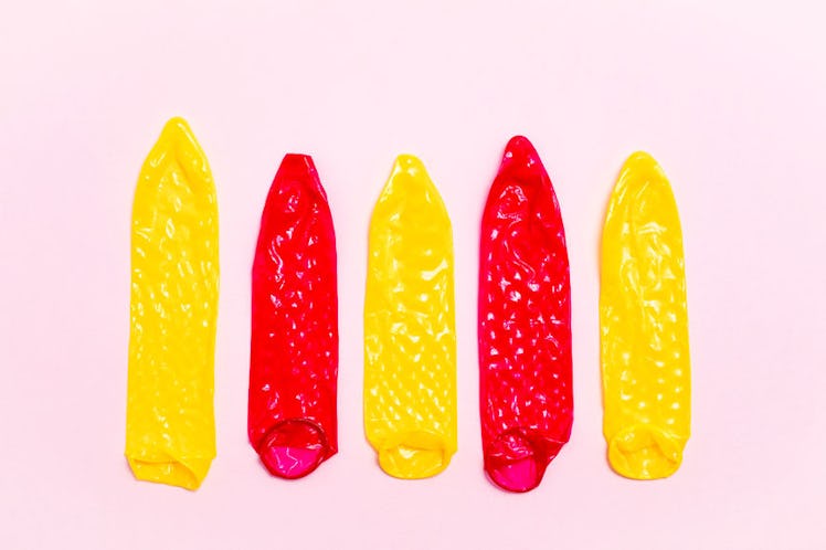 Three yellow and two red stretched condoms