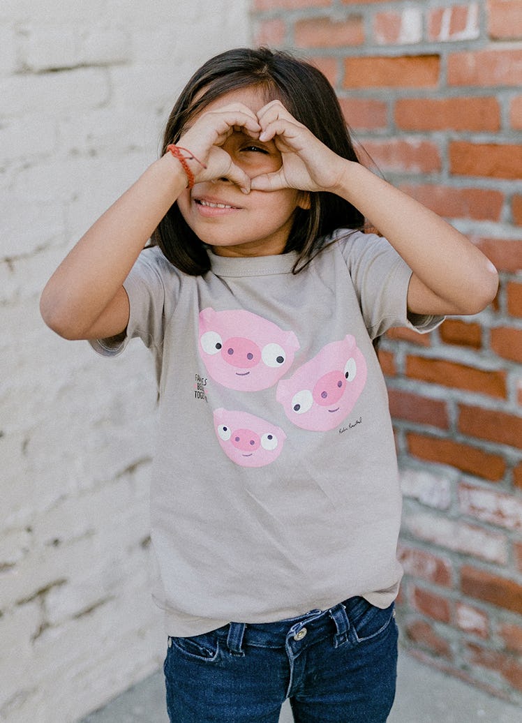 A little girl posing in a Winter Water Factory x Families Belong Together capsule collection grey sh...