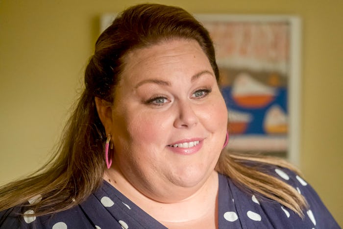 A close-up portrait of Kate from 'This Is Us' smiling in a navy-white polka-dot dress