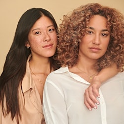 Two women posing with no makeup on, only Onekind skincare products