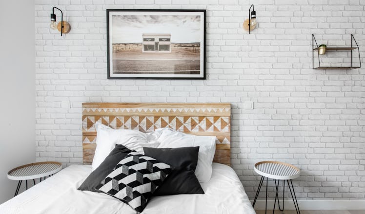 A trendy studio apartment in Paris on Airbnb has a bed with black and white pillows and wooden accen...