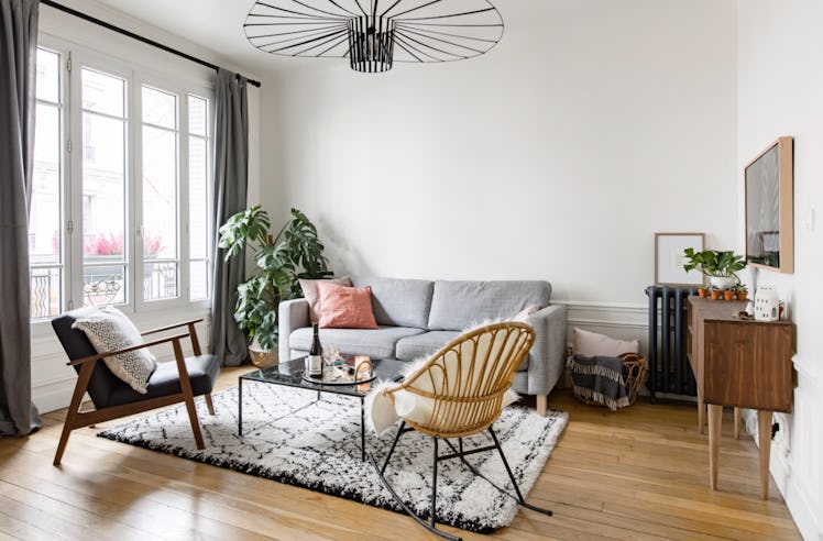 A stylish apartment you can stay in in Paris has a grey couch, modern decor, and a historical atmosp...