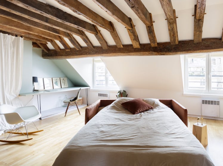 A cozy bed with a pink pillow in a loft in Paris is where you should relax on your next trip.
