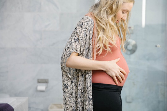 is smell discharge a sign of labor,  pregnant woman looking at her belly in the bathroom