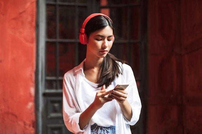 A woman in a white blouse scrolls on her phone. Set limits on your screen time in order to use your phone more mindfully