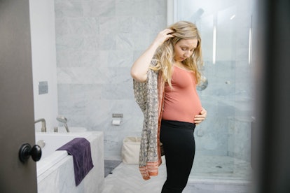is smelly discharge a sign of labor, pregnant woman looking at her belly in the bathroom