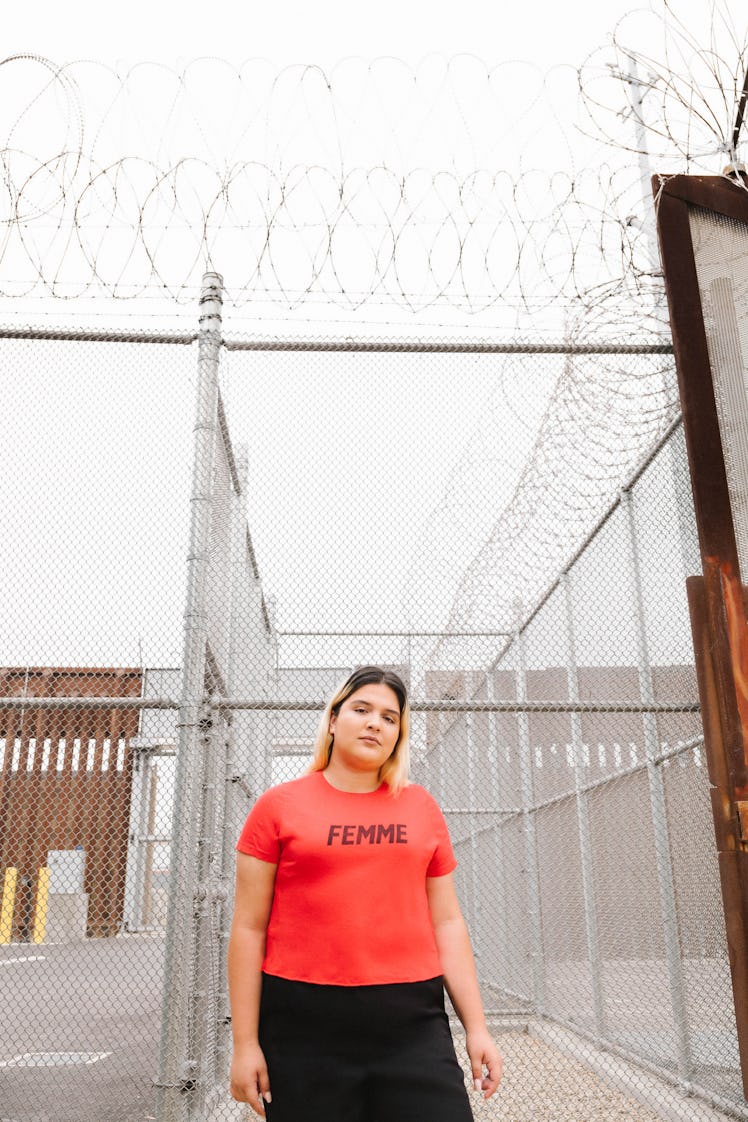 Activist Sara Mora with Girls Who Code & Team Sisterhood stands at a fence at the U.S. Mexico border