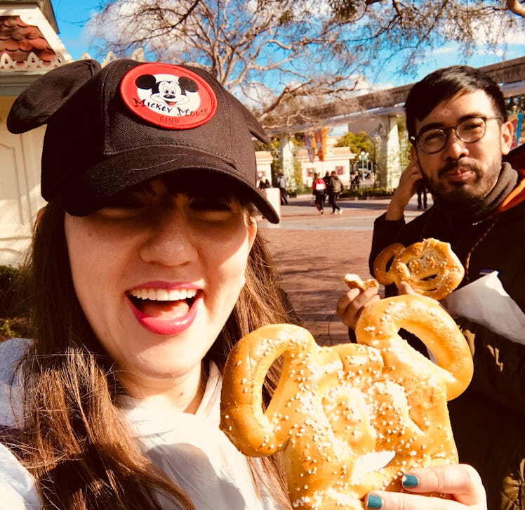 a woman and man eating Mickey pretzels at Disney is always a fun Disneyland activity for couples.