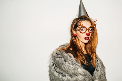 A girl is dressed up like a reindeer with antlers, a furry coat, and glasses on Halloween.
