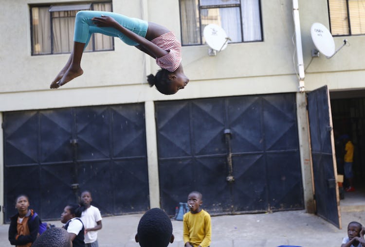 A girl hangs upside down in air with back arched, as she jumps on a trampoline in South Africa.