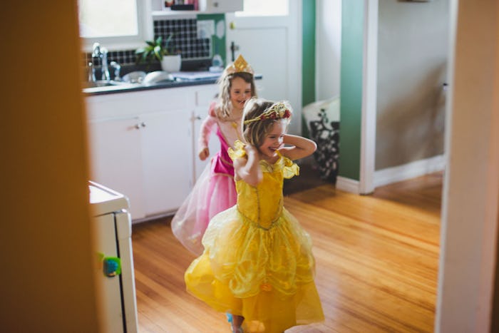Two young girls in a yellow and pink princess dress run through a doorway.