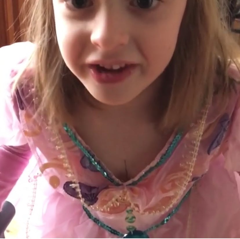 Young girl in pink princess dress looks at camera.