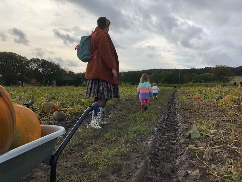 A woman walking with her two daughters in a pumpkin field 