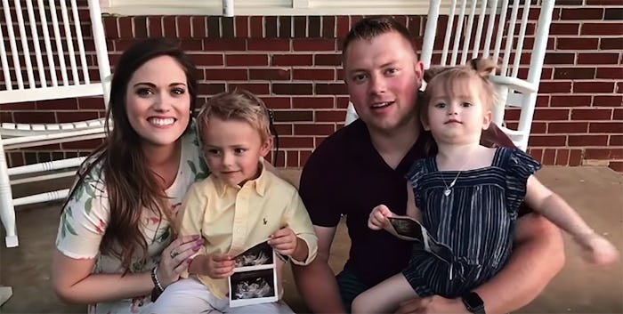 Whitney and Zach Bates posing with their two kids and an ultrasound of their third
