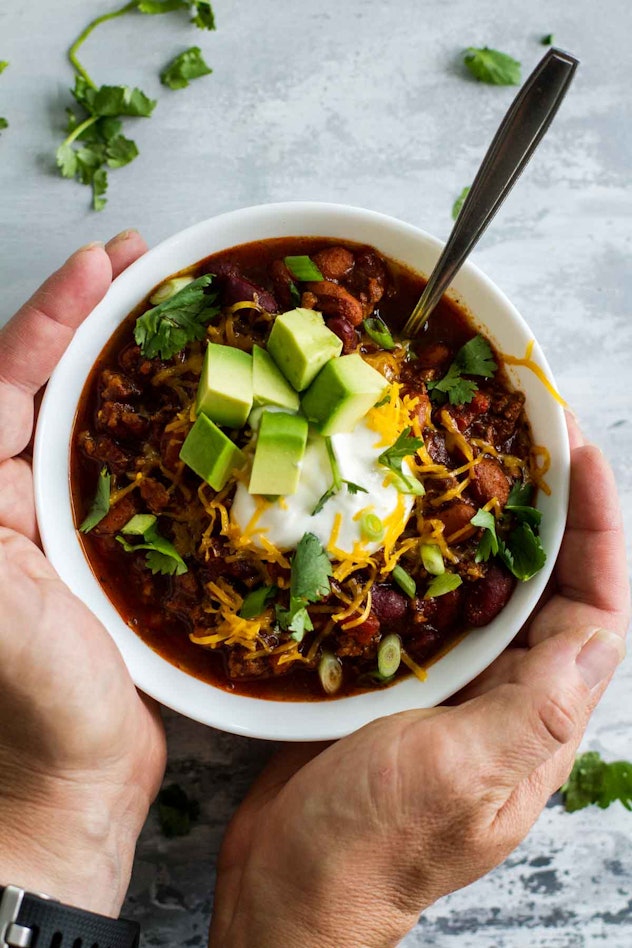 Hands holding a cup of slow cooker chili