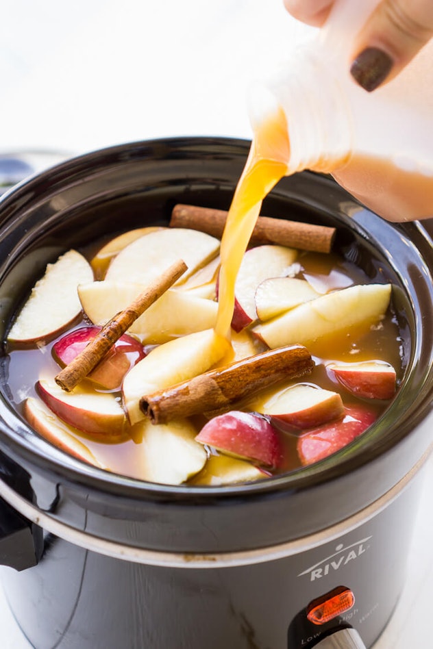 sliced apples, cinnamon sticks, cider and rum cooking in slow cooker