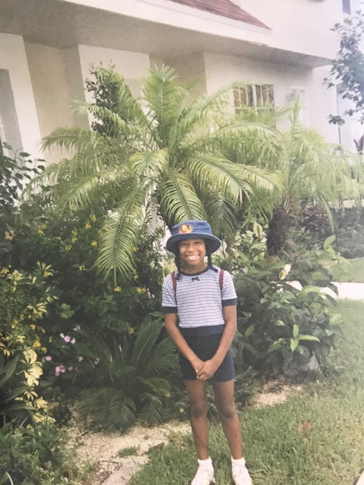 A picture of the author as a young child, standing and smiling for the camera.