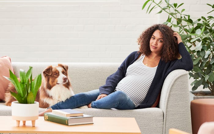 Woman in maternity clothes on couch with dog