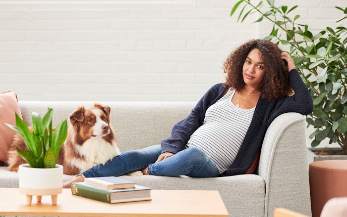 Woman in maternity clothes on couch with dog