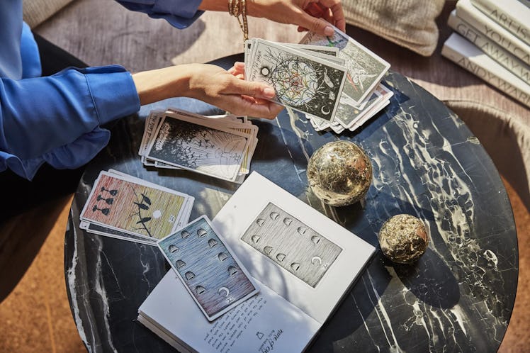 A woman reads tarot cards on a black marble table.