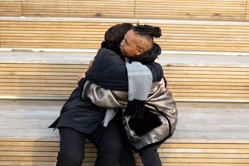 Two people embrace in a hug on a bench outside in chilly weather. Spirit Day increases visibility fo...