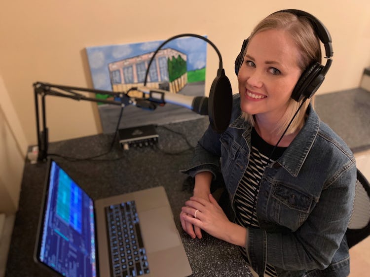 a woman recording a podcast sits in front of her laptop with headphones and a microphone