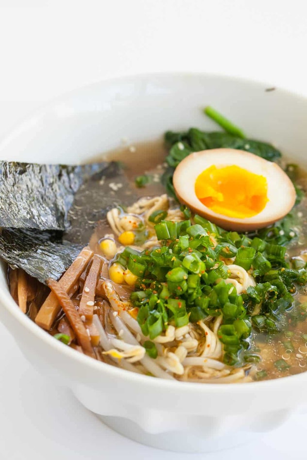 Instant pot ramen noodle soup with chopped green onions, dried seaweed, and a half-boiled egg. 