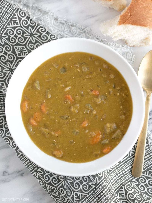 A white bowl full of split pea soup rests on a tribal print cloth. 