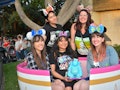 A group of friends wearing Minnie ears are sitting in a teacup spending a day at Disneyland.