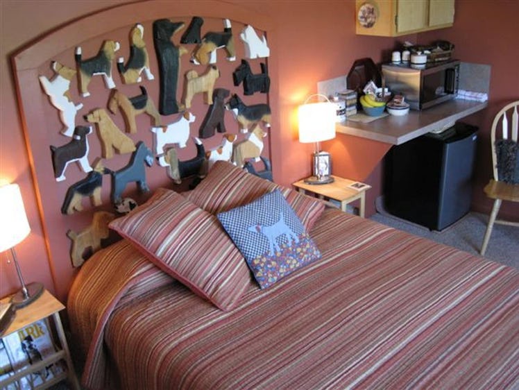 This cozy bedroom inside the Dog Bark Park Inn B&B has a dog-themed headboard and bed with three thr...