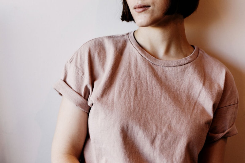 A woman in early menopause wearing a pink shirt while standing in front of a wall