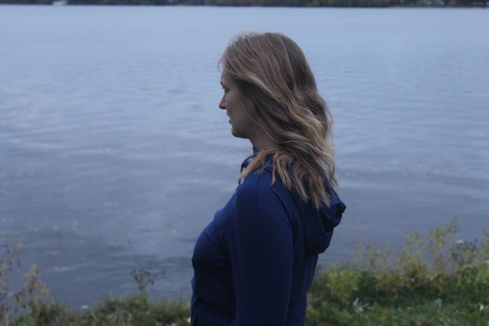A woman looking at the lake after her First Trimester Miscarriage