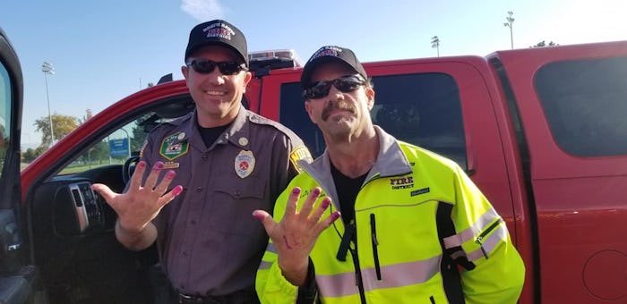 Two firemen model their freshly painted nails after rescuing a little girl from a car accident. 