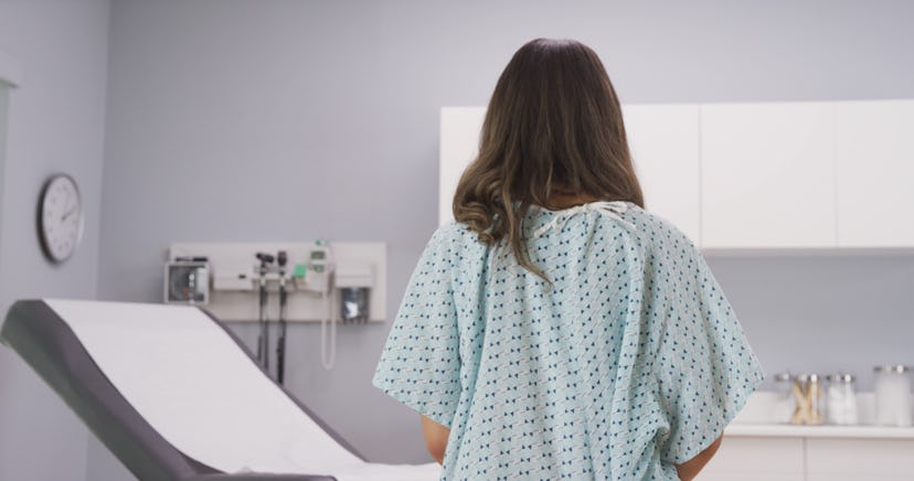 A person sits in a hospital gown on a doctor's table. Breast cancer's link to family history is comp...