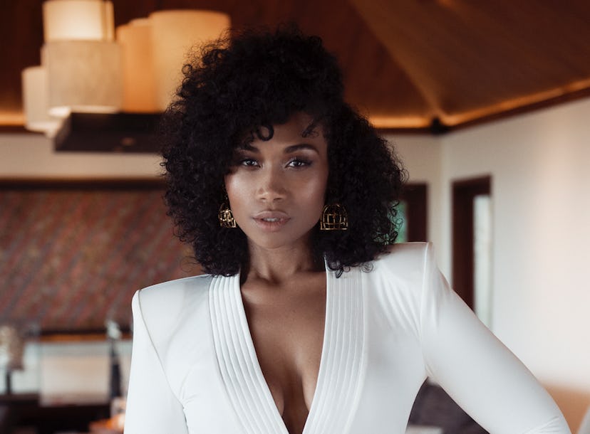 Young black lady with curly hair posing in a white blazer