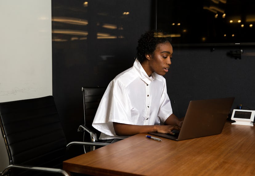 A non-binary person using a laptop at work. Employees who are multiply marginalized are more likely ...