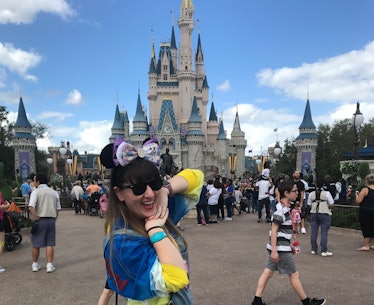 A woman posing in front of Cinderella's castle at Disney World. 