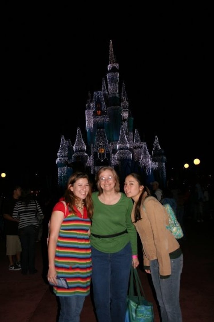 A family poses in front of Cinderella's castle in Disney World at night. 