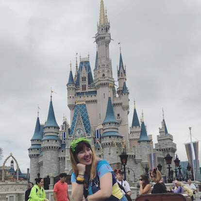 A woman smiles and poses in front of Cinderella's castle at Disney World. 