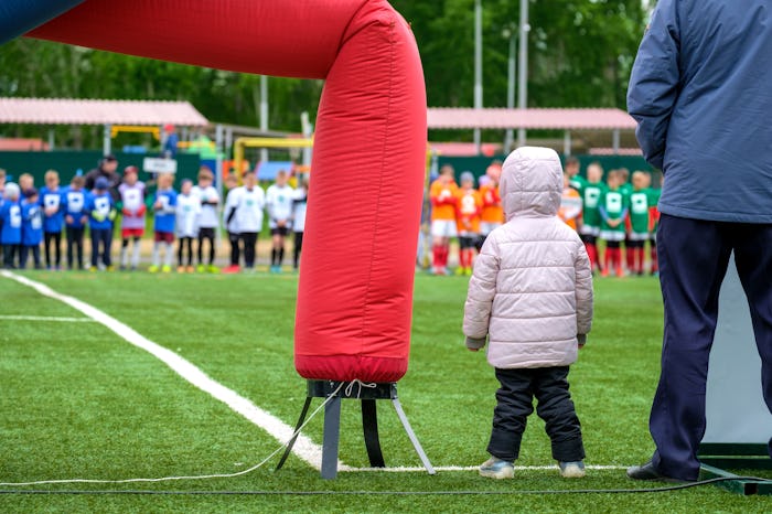 adult and kid bundled up on the sidelines of a soccer game