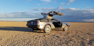 The Delorean DMC-12 car from 'Back to the Future' has vertical-opening doors and is parked in the su...