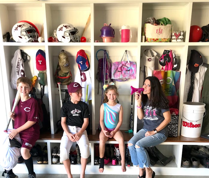 A mom and three kids sit in their mud room.
