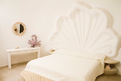 A bedroom in the Seashell House on Airbnb has a shell headboard and decorative mirror.