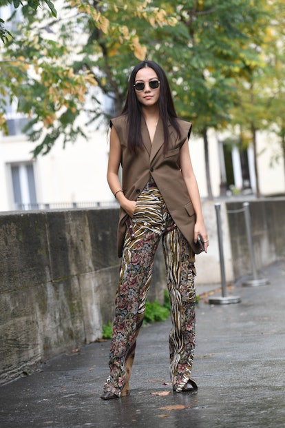 Street style photo of influencer Yoyo Cao wearing a long vest over statement print pants at Fashion ...