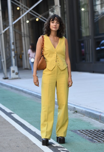 Street style photo of influencer Alyssa Coscarelli wearing a yellow vest and matching trousers with ...
