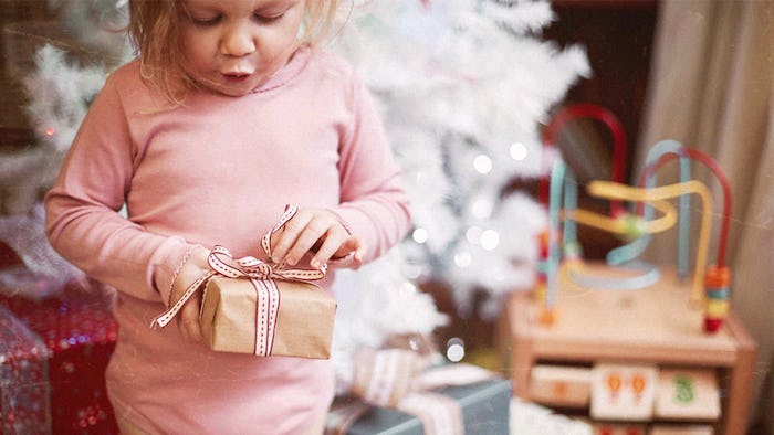 A young child opens up holiday gifts.