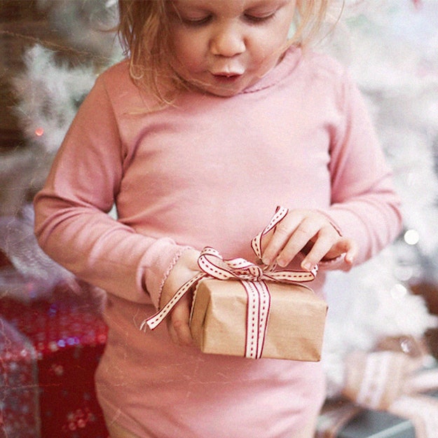 A young child opens up holiday gifts.