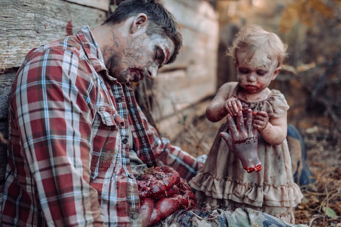 A zombie baby eats the hand of her father during a photoshoot.